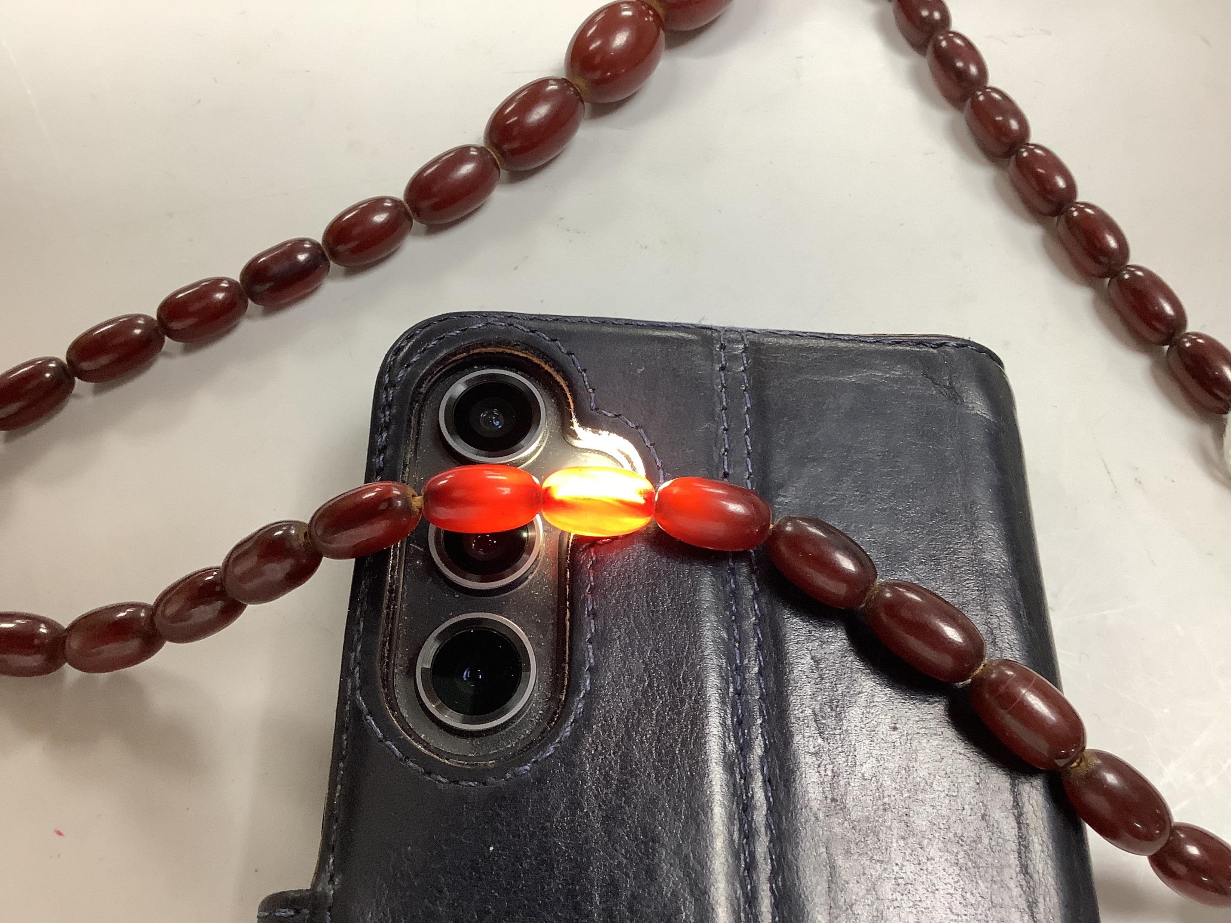 A cherry-coloured bakelite 'amber' necklace, composed of graduated oval beads measuring approximately 1.1-3cm, length 76cm, gross weight 66 grams, Condition: good, minor wear